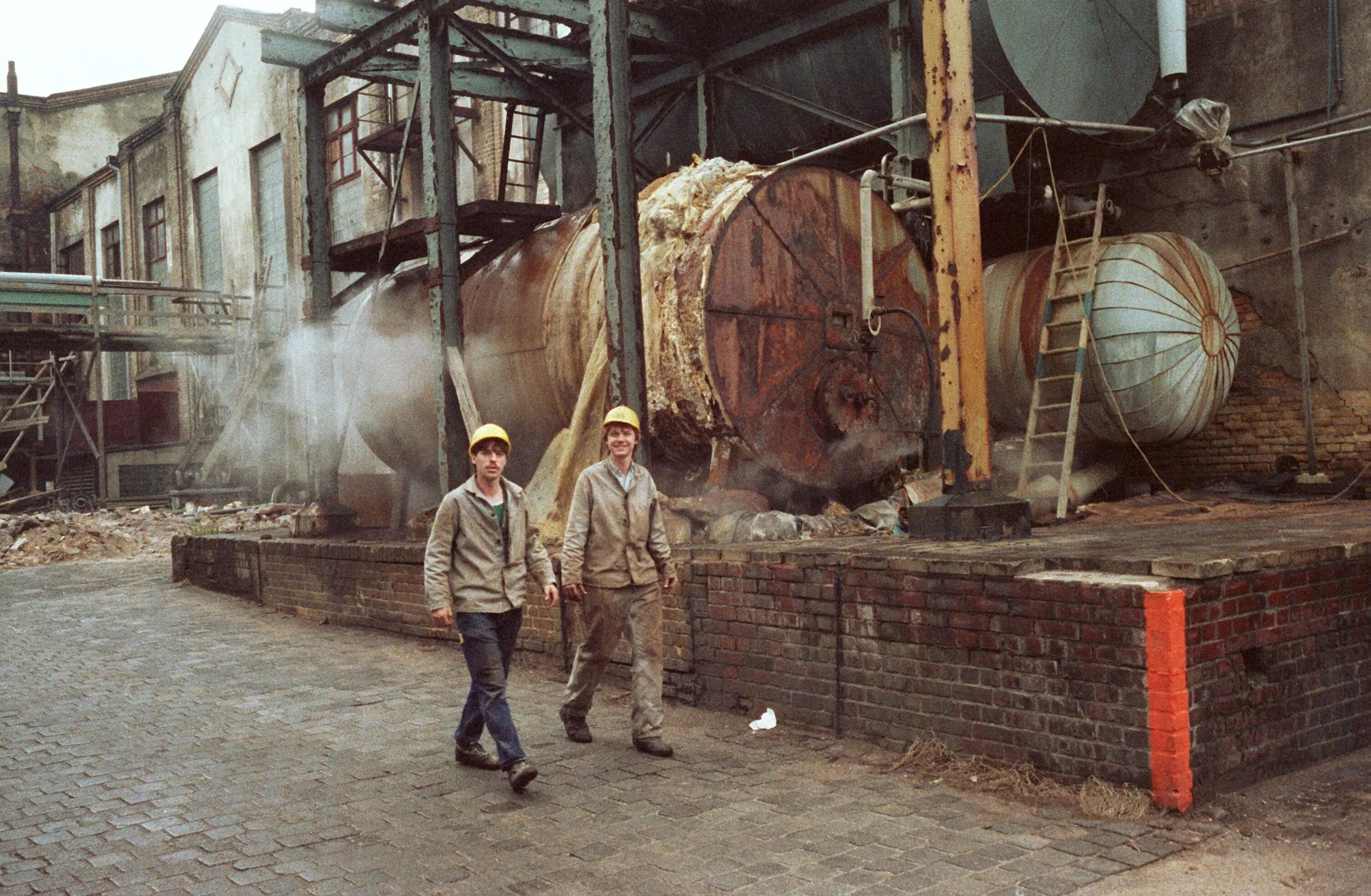 Arbeiter vor einem völlig verrosteten Anlagenteil in einem Chemiewerk