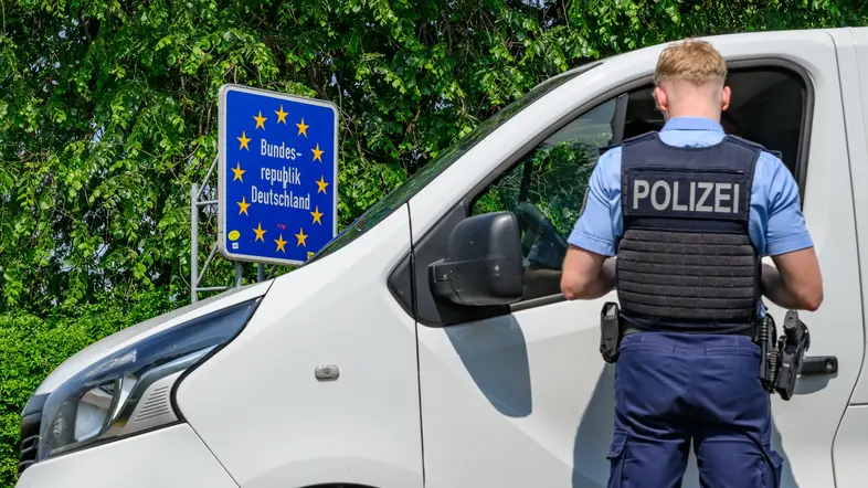 Ein Polizist kontrolliert ein Auto an der Grenze