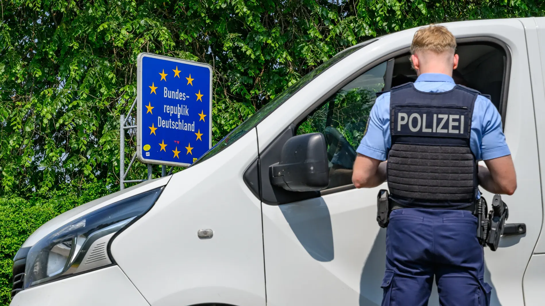 Ein Polizist kontrolliert ein Auto an der Grenze