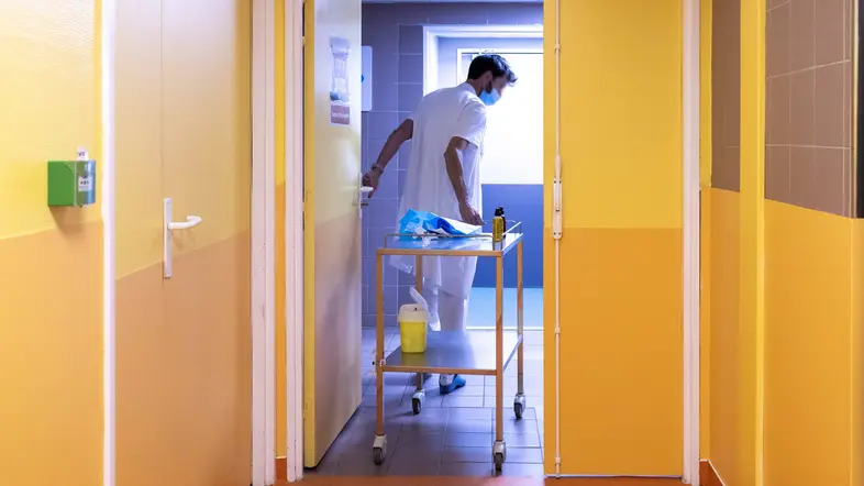 Ein Pfleger zieht einen Waagen hinter sich her.