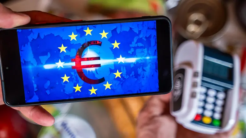 Ein Kunde bezahlt seinen Einkauf mit dem digitalen Euro per Smartphone und Kartenlesegerät.