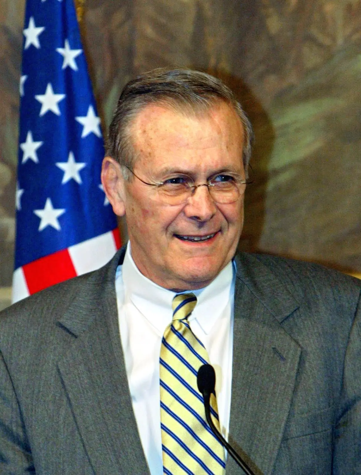 Portätfoto von Donald Rumsfeld vor der Amerikanischen-Flagge