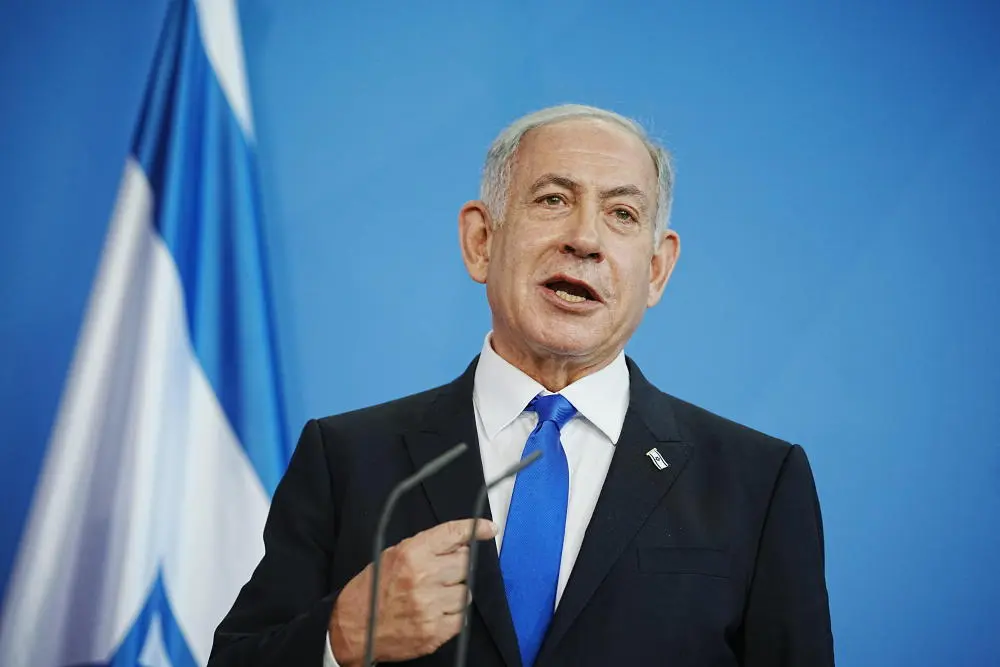 Benjamin Netanjahu Benjamin Netanjahu steht vor einem Mikrofon, hinter ihm eine israelischen Fahne.