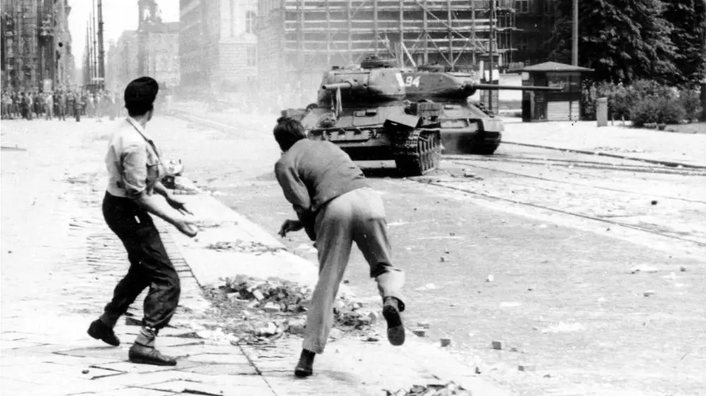 Zwei Demonstranten werfen Steine auf einen sowjetischen Panzer in Ostberlin. 