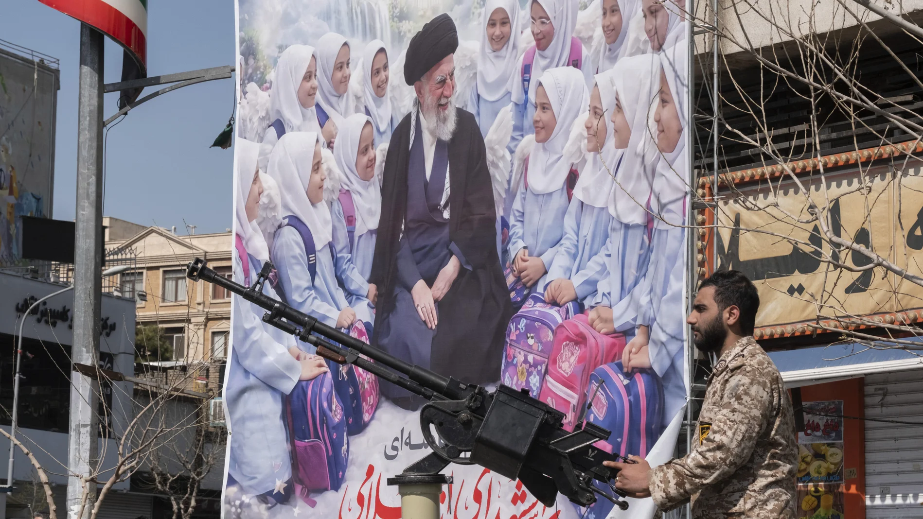 Bewaffneter Soldat steht vor einem Plakat von Ayatollah Ali Khamenei