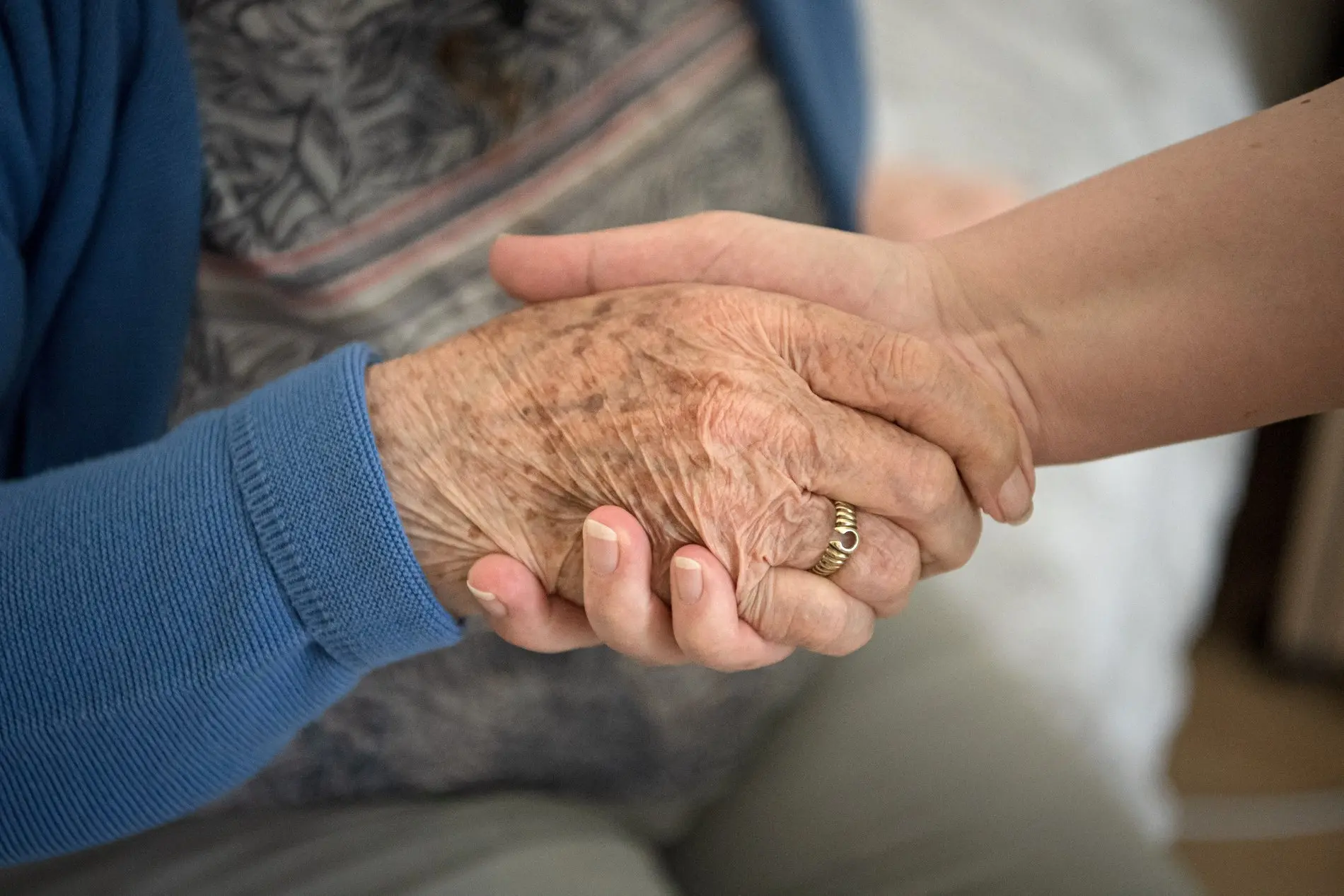 Eine Aufnahme einer Pflegekraft, die die Hand einer Seniorin hält