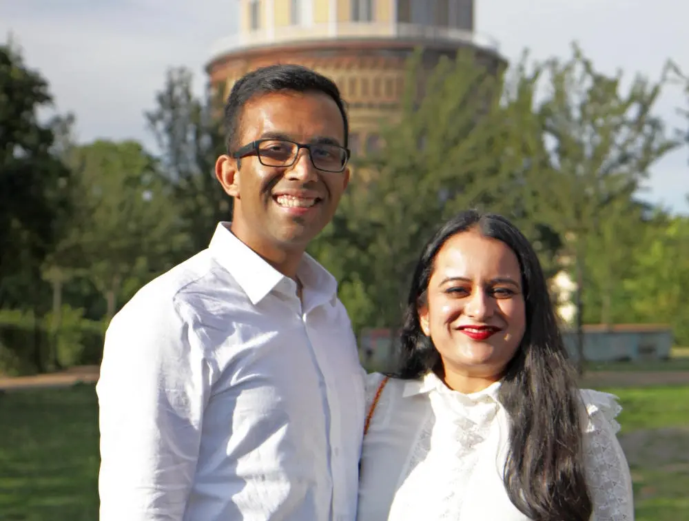 Varun und Bhavna lächelnd mit Brille und weißen Oberteilen
