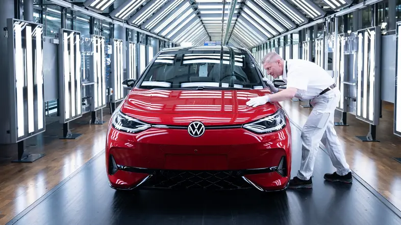 Ein Mitarbeiter inspiziert im Lichttunnel in der Gläsernen Manufaktur von Volkswagen einen VW ID.3.