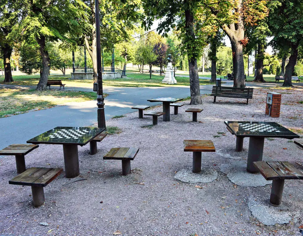 Menschenleere Sitzgruppen mit Bänken in einem Park.