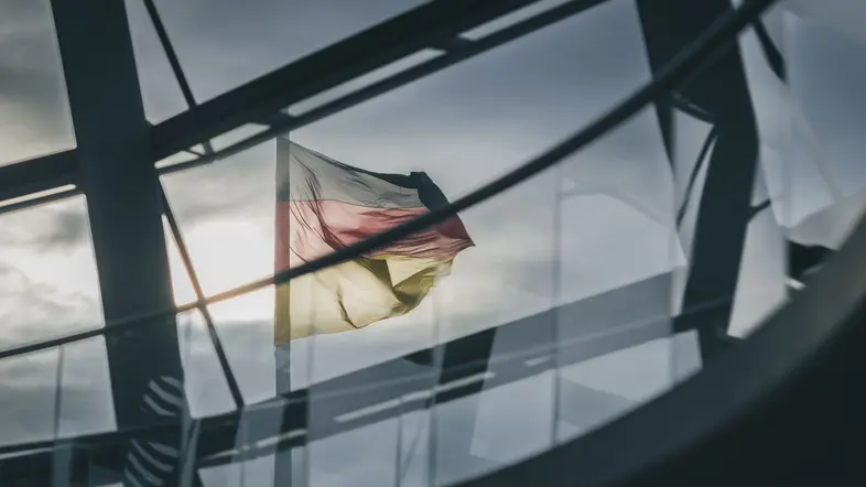 Blick durch gläserne Kuppel des Reichstagsgebäudes auf die deutsche Fahne