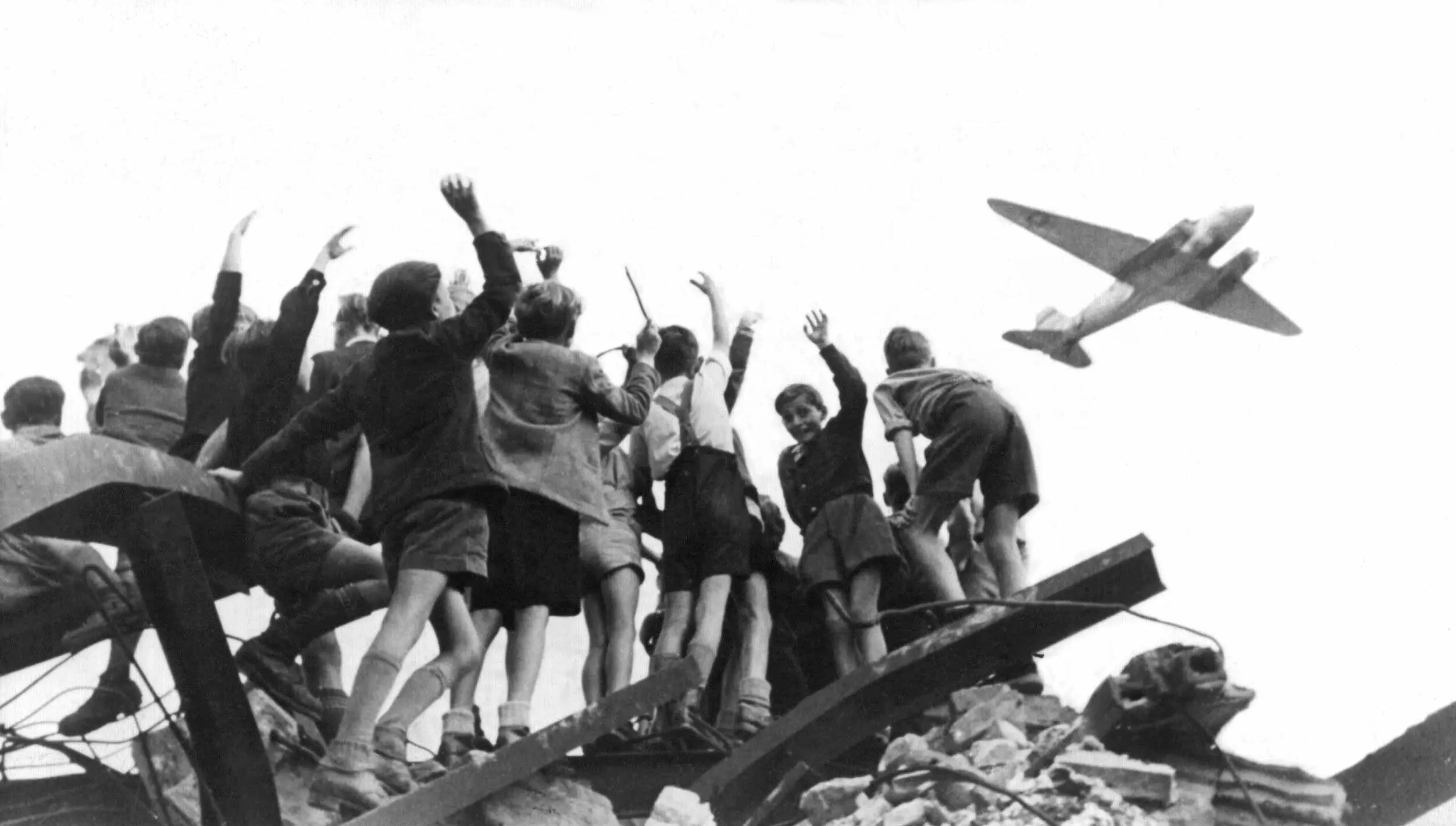 Kinder winken einem Rosinenbomber