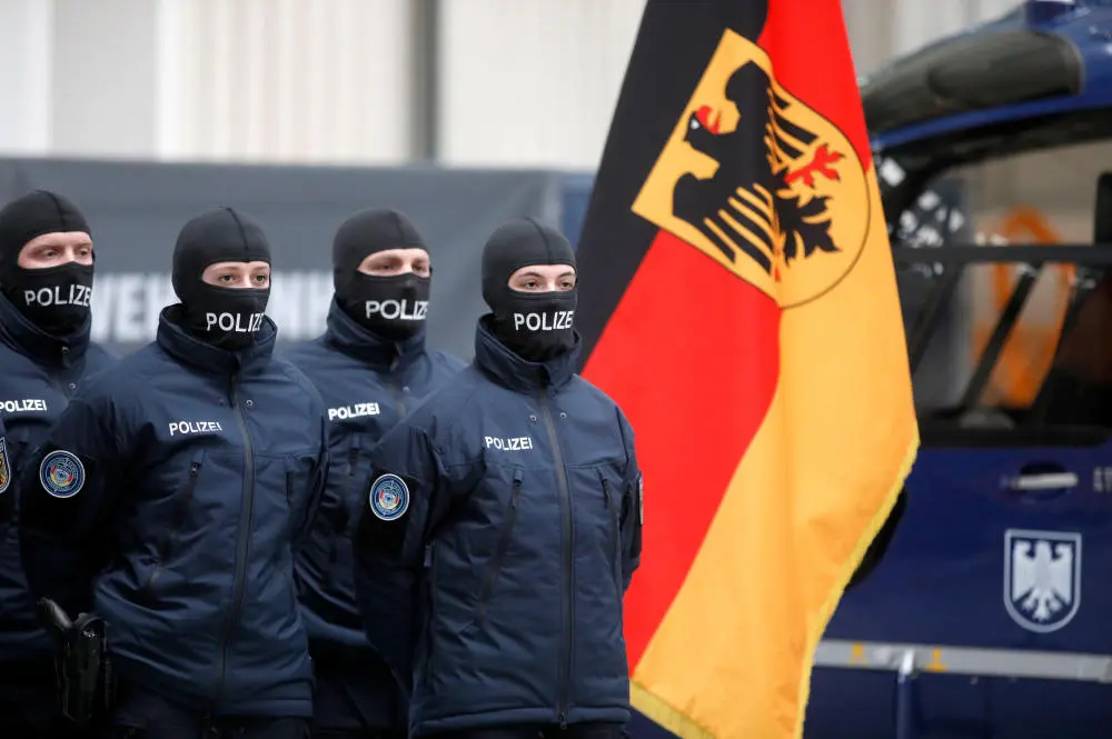Bundespolizisten mit Sturmhauben vor der deutschen Flagge