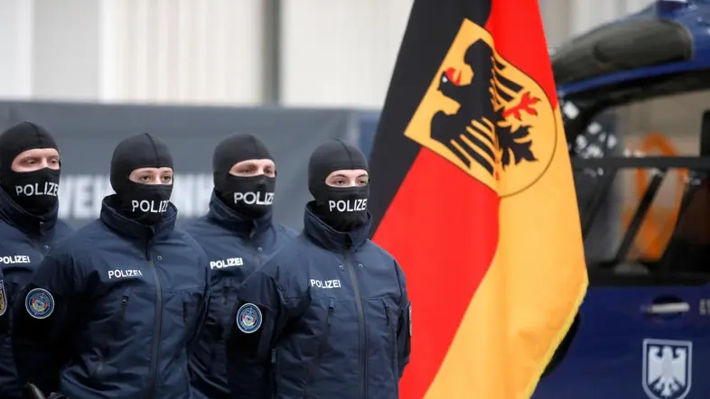 Bundespolizisten mit Sturmhauben vor der deutschen Flagge