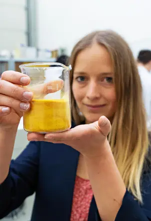 Anne Lamp hält ein Glas mit dem Granulat in die Kamera.