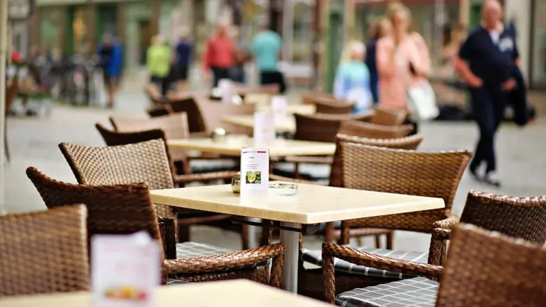 Menschenleere Gastronomietische im Außenbereich.