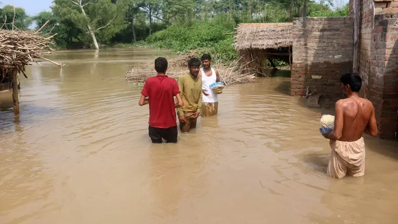 Zu sehen sind Menschen in einer überfluteten Ortschaft.  