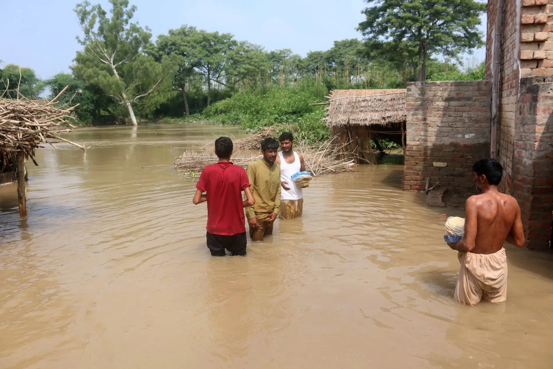 Zu sehen sind Menschen in einer überfluteten Ortschaft.  