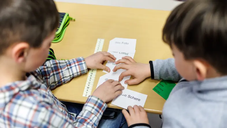 Grundschüler sitzen an einem Tisch.