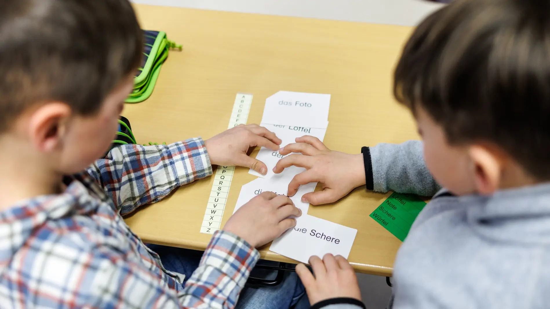 Grundschüler sitzen an einem Tisch.