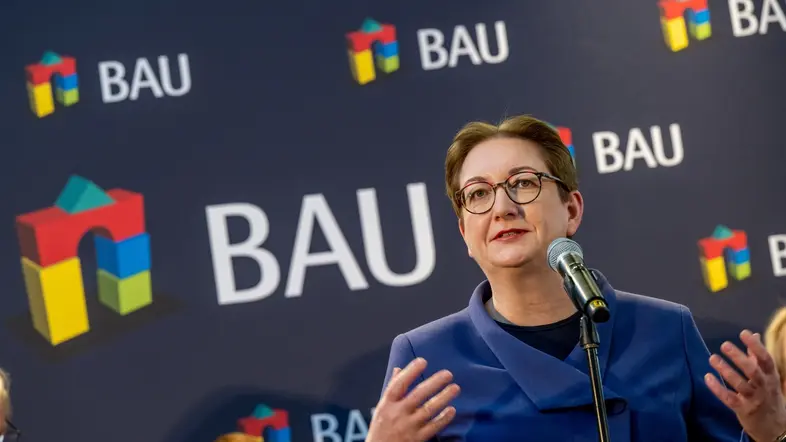 Klara Geywitz im blauen Blazer und mit Brille am Rednerpult der Baumesse