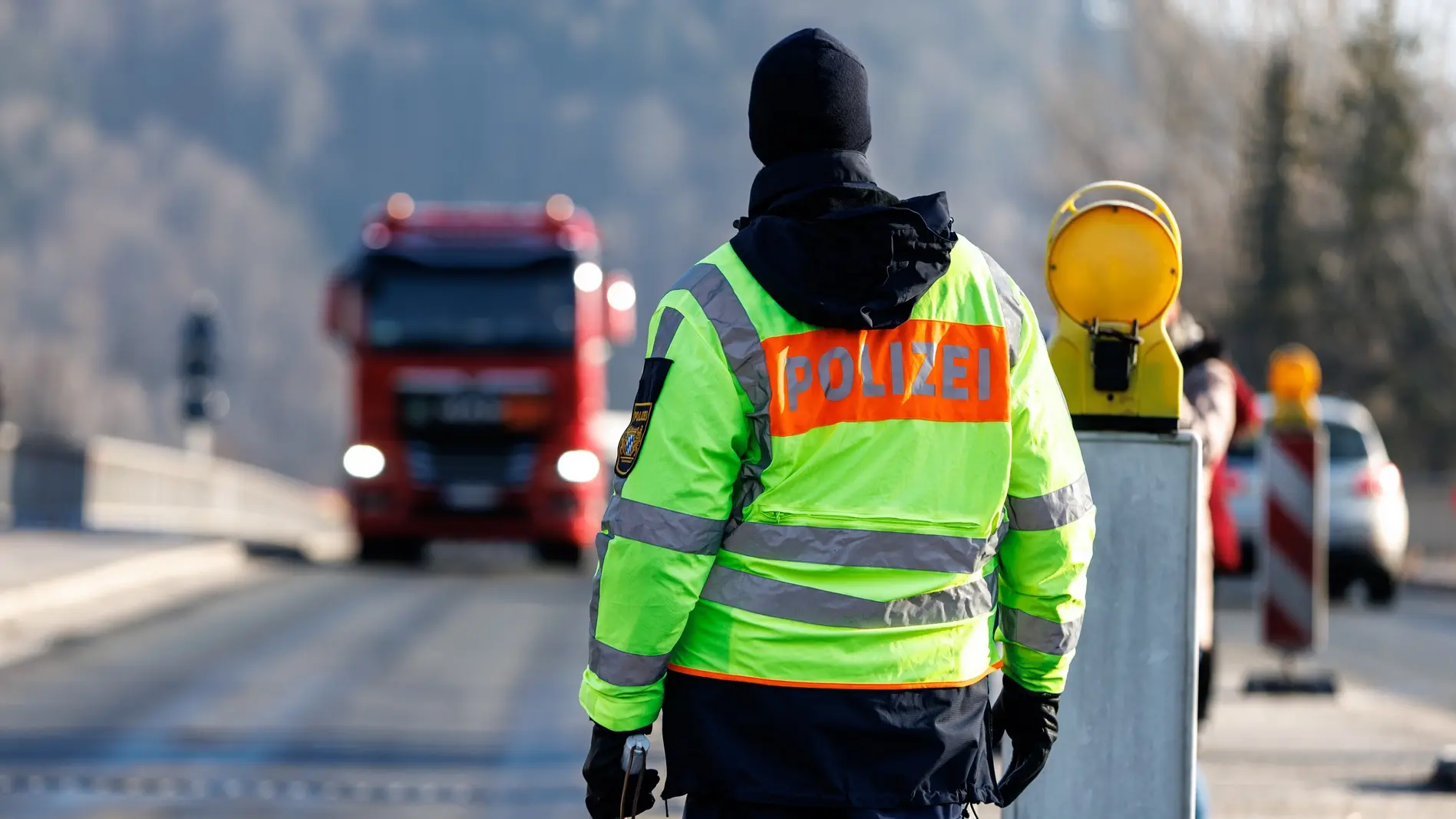 Polizist mit Signalschild von hinten