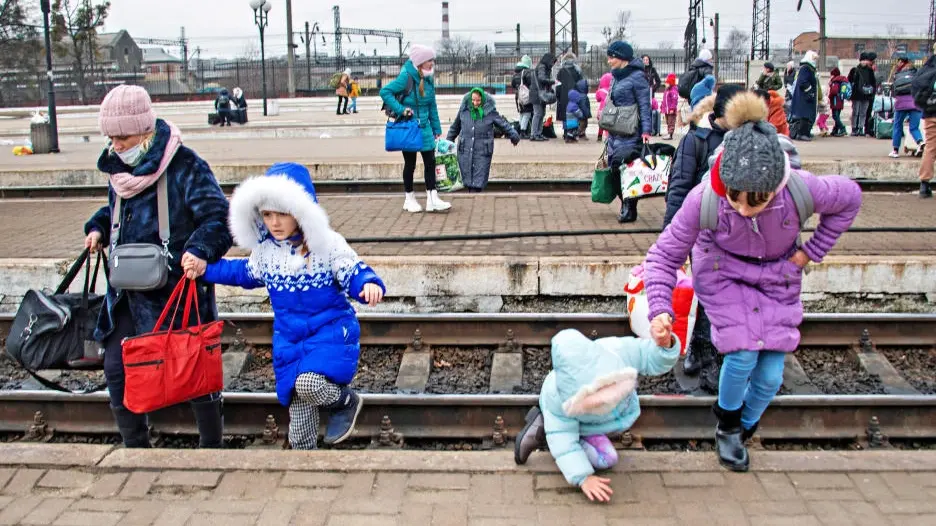 Das Bild zeigt eine Mutte mit drei Töchtern, die in Lwiw Bahngleise überqueren.