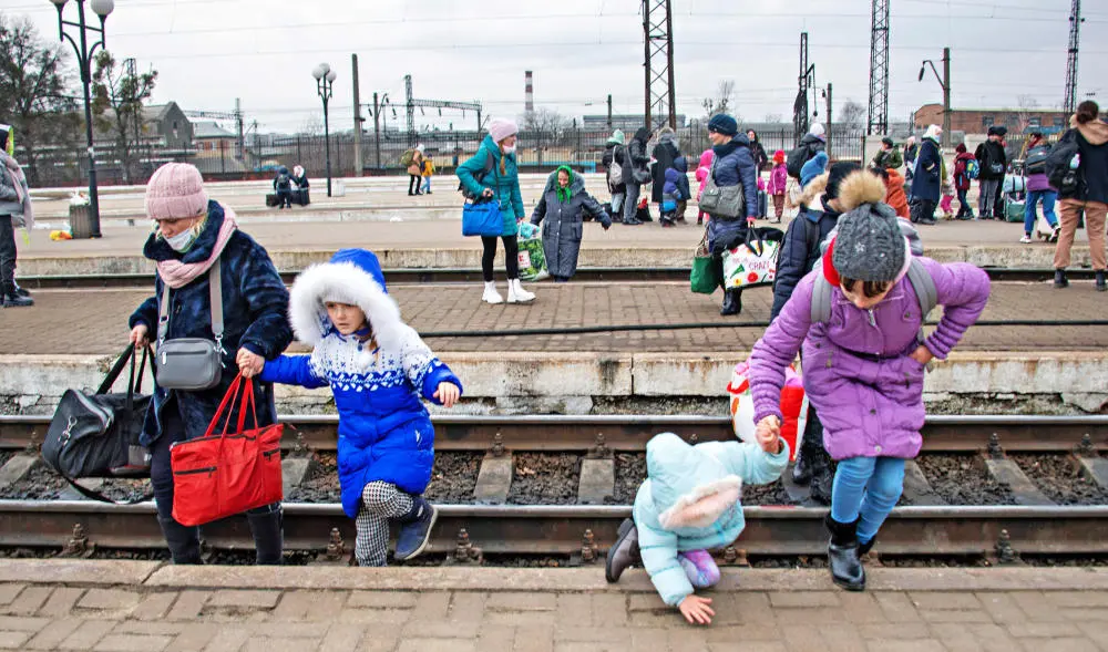 Ukrainische Flüchtlinge in Lwiw Das Bild zeigt eine Mutter mit drei Töchtern an einen Bahnhof, wie sie gerade Gleise überqueren.