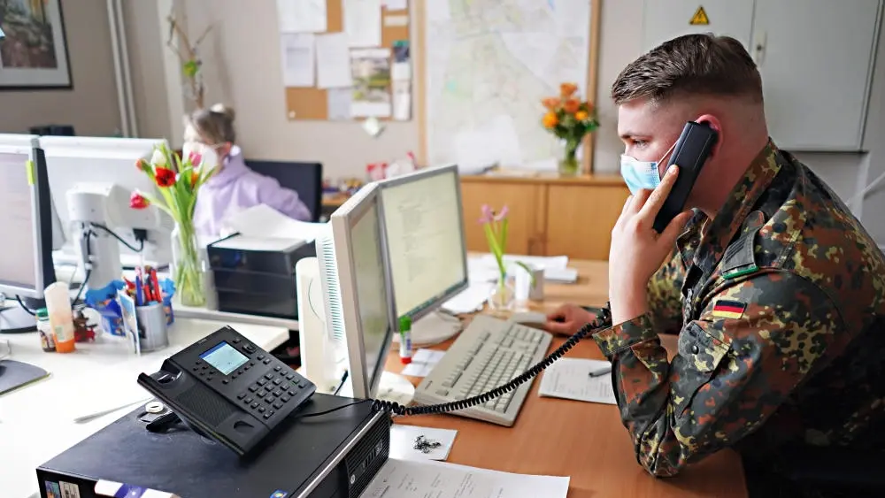 Soldat in Uniform telefonierend am Schreibtisch.