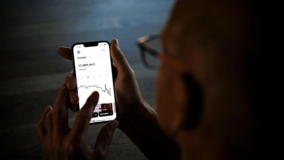 Mann hält Smartphone mit Aktienkurs