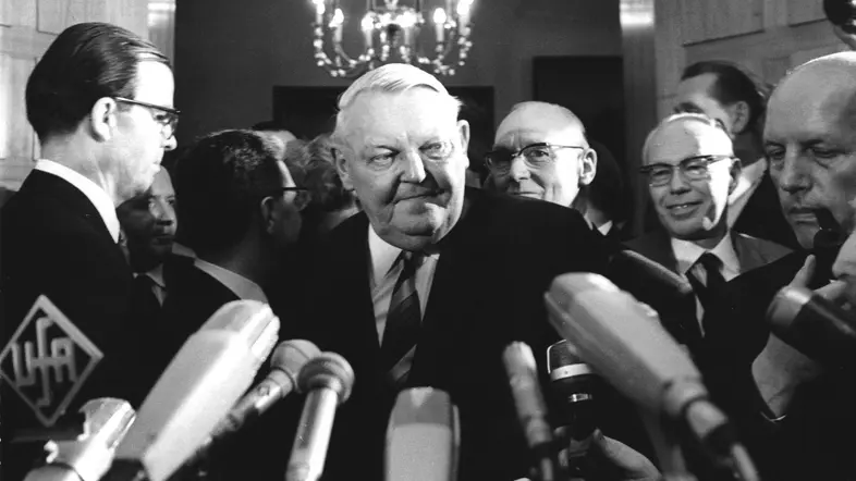 Ludwig Erhard vor Mikrofonen von Pressevertretern