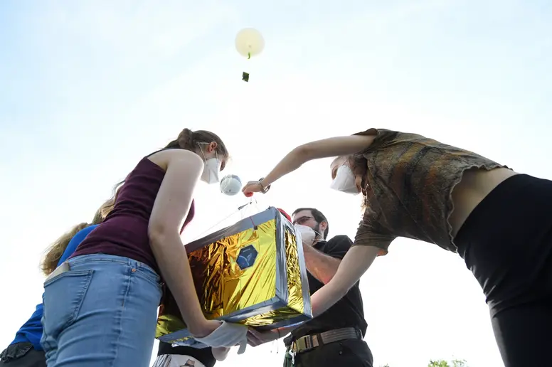 Studenten der TU München halten den Prototypen eines Kleinsatelliten bei dessen Start.