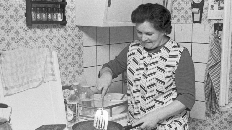 Ältere Frau steht am Küchenherd