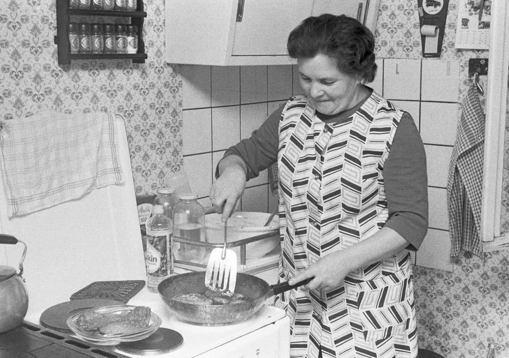 Ältere Frau steht am Küchenherd