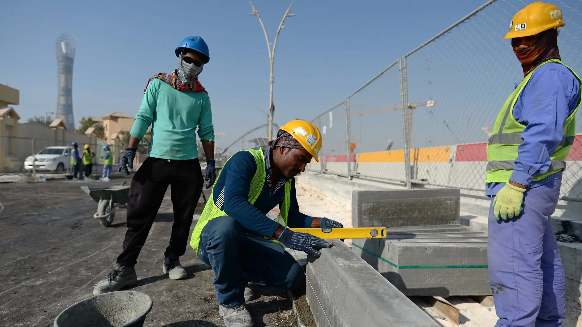 Zu sehen sind mehrere Bauarbeiter aus Indien, die in Doha eine Straße ausbessern. 