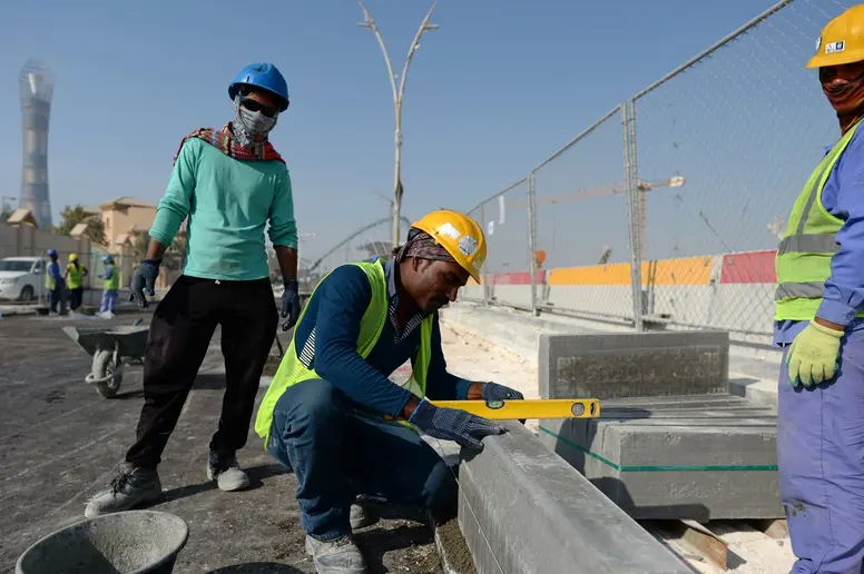 Zu sehen sind mehrere Bauarbeiter aus Indien, die in Doha eine Straße ausbessern. 