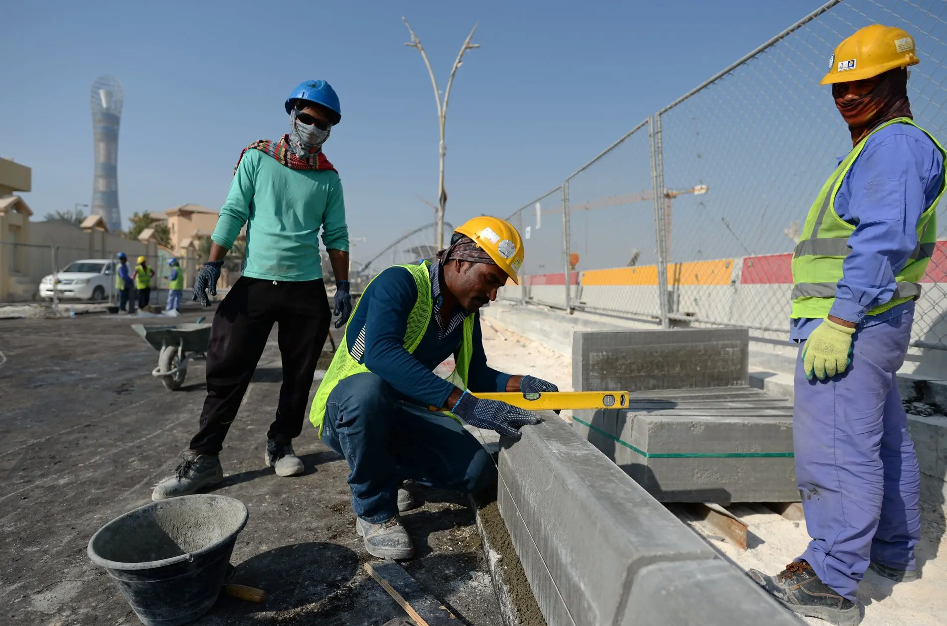 Zu sehen sind mehrere Bauarbeiter aus Indien, die in Doha eine Straße ausbessern. 
