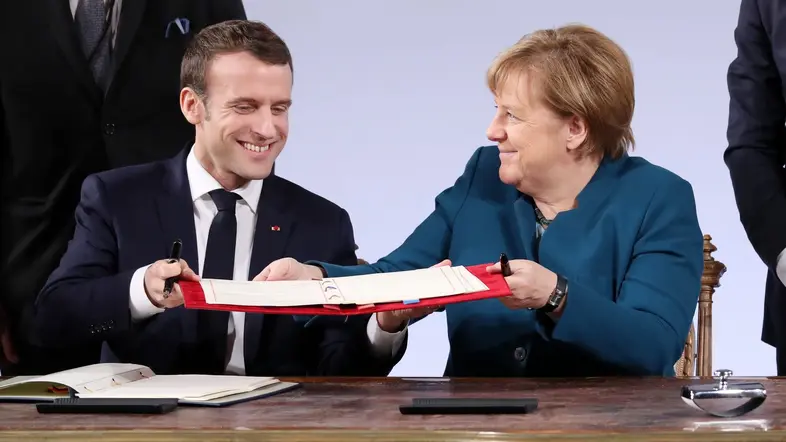 Angela Merkel und Emmanuel Macron halten den Vertrag von Aachen in der Hand