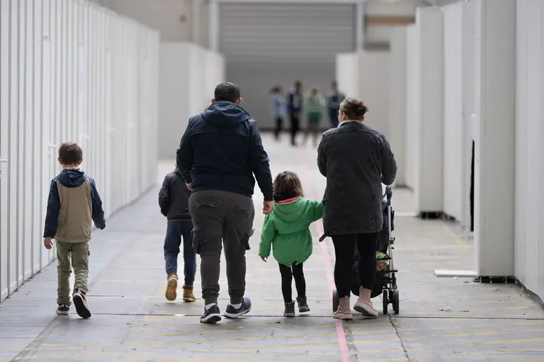 Eine Flüchtlingsfamilie geht durch die zu einer Massenunterkunft umfunktionierten Messehalle in Frankfurt.