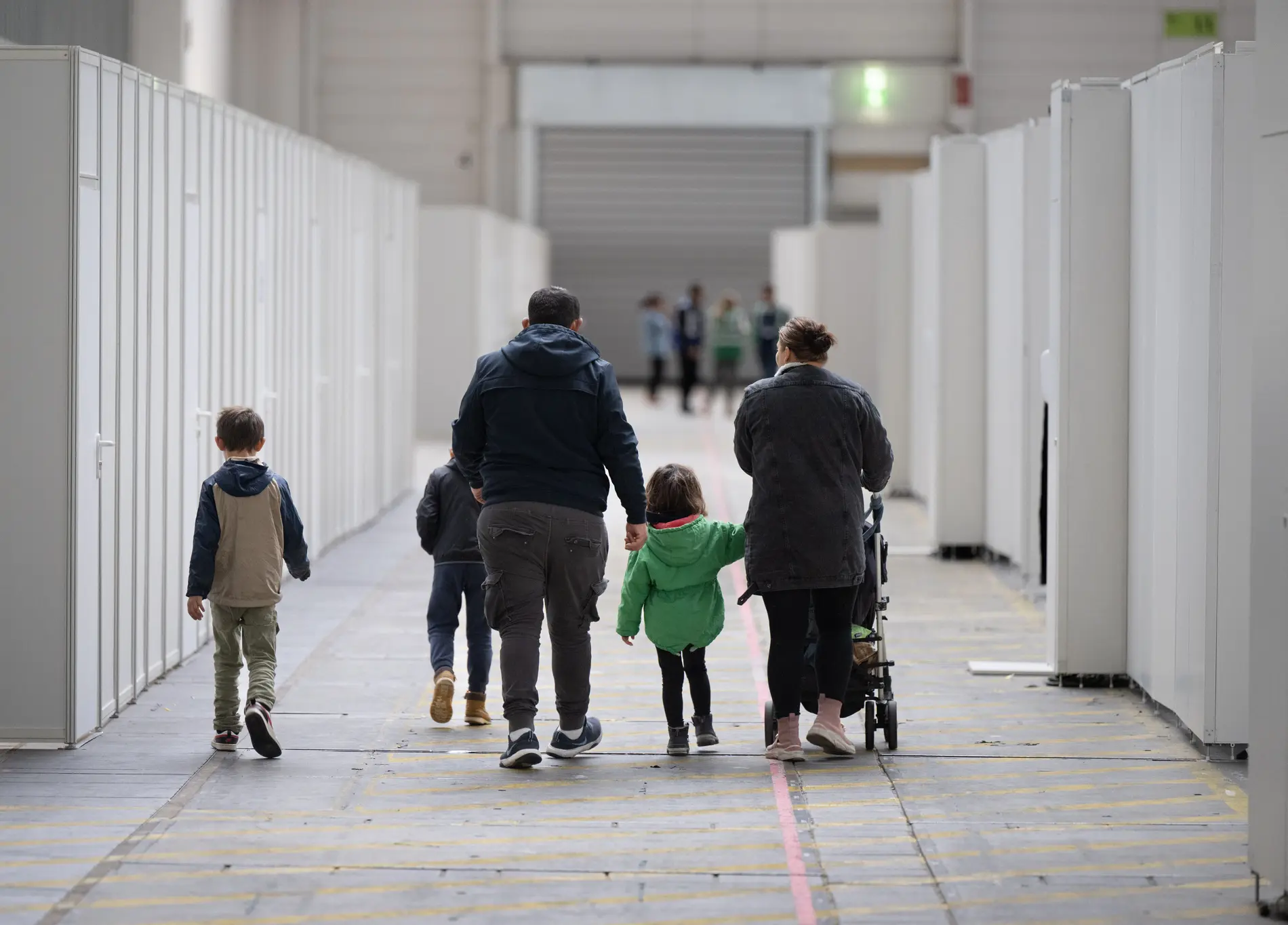 Familiennachzug Eine Flüchtlingsfamilie geht durch die zu einer Massenunterkunft umfunktionierten Messehalle in Frankfurt.