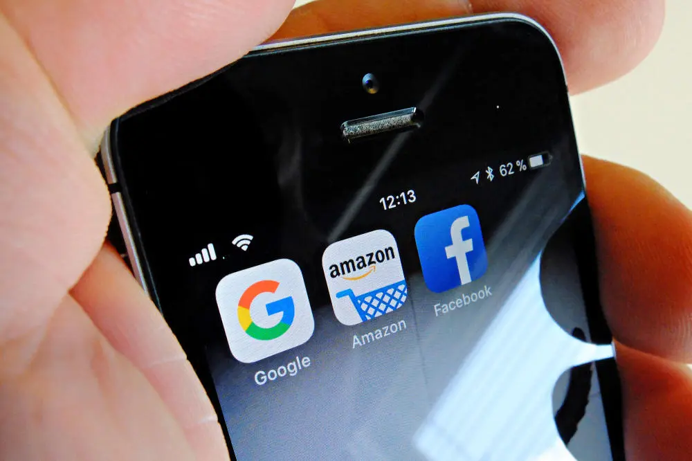 Logos von Google, Amazon und Facebook auf dem Display eines iPhones