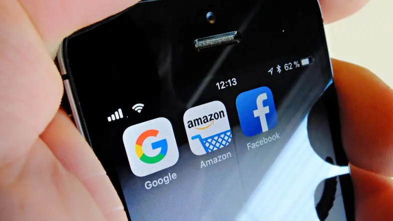 Logos von Google, Amazon und Facebook auf dem Display eines iPhones