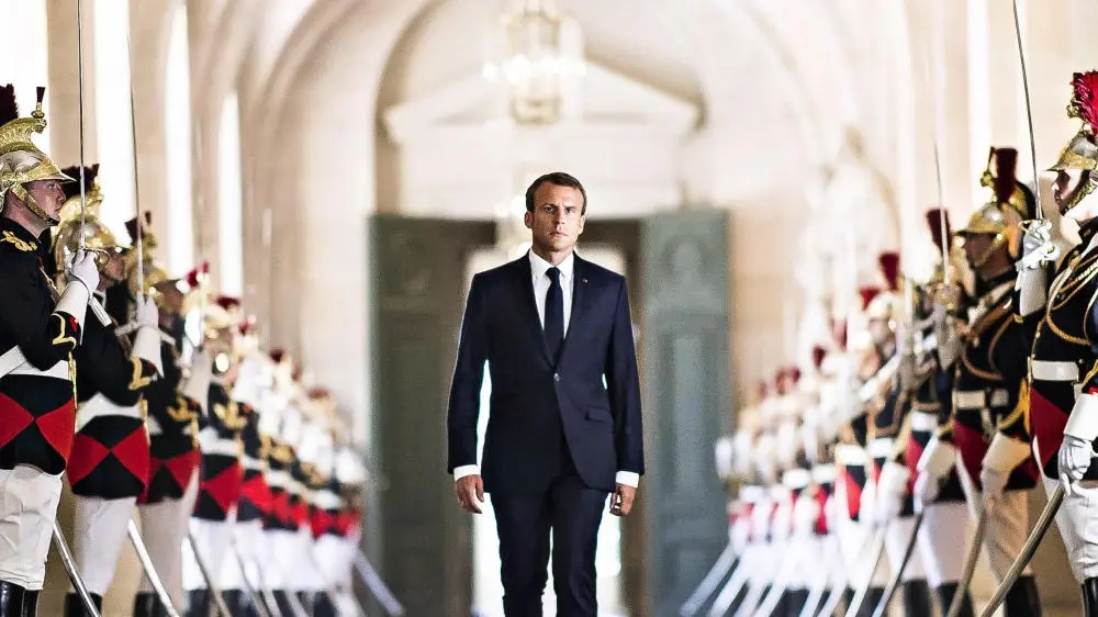 Fankreichs Präsident Emmanuel Macron geht umrahmt von Soldaten durch das Schloss Versailles.