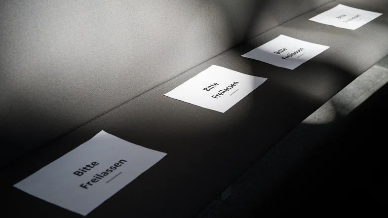 Schilder mit der Aufschrift "Bitte Freilassen" liegen auf den Besuchersitzen.