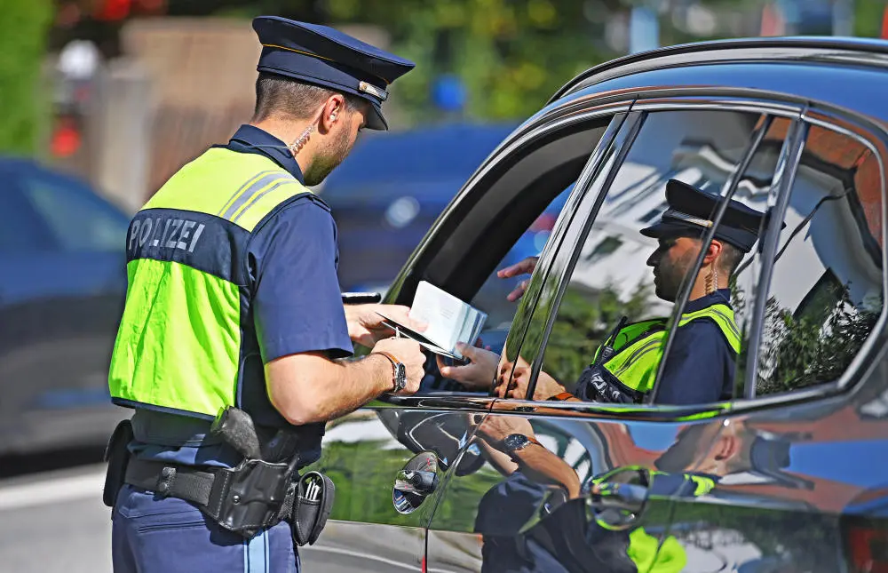 Grenzkontrollen Grenzpolizist kontrolliert die Papiere eines Autofahrers
