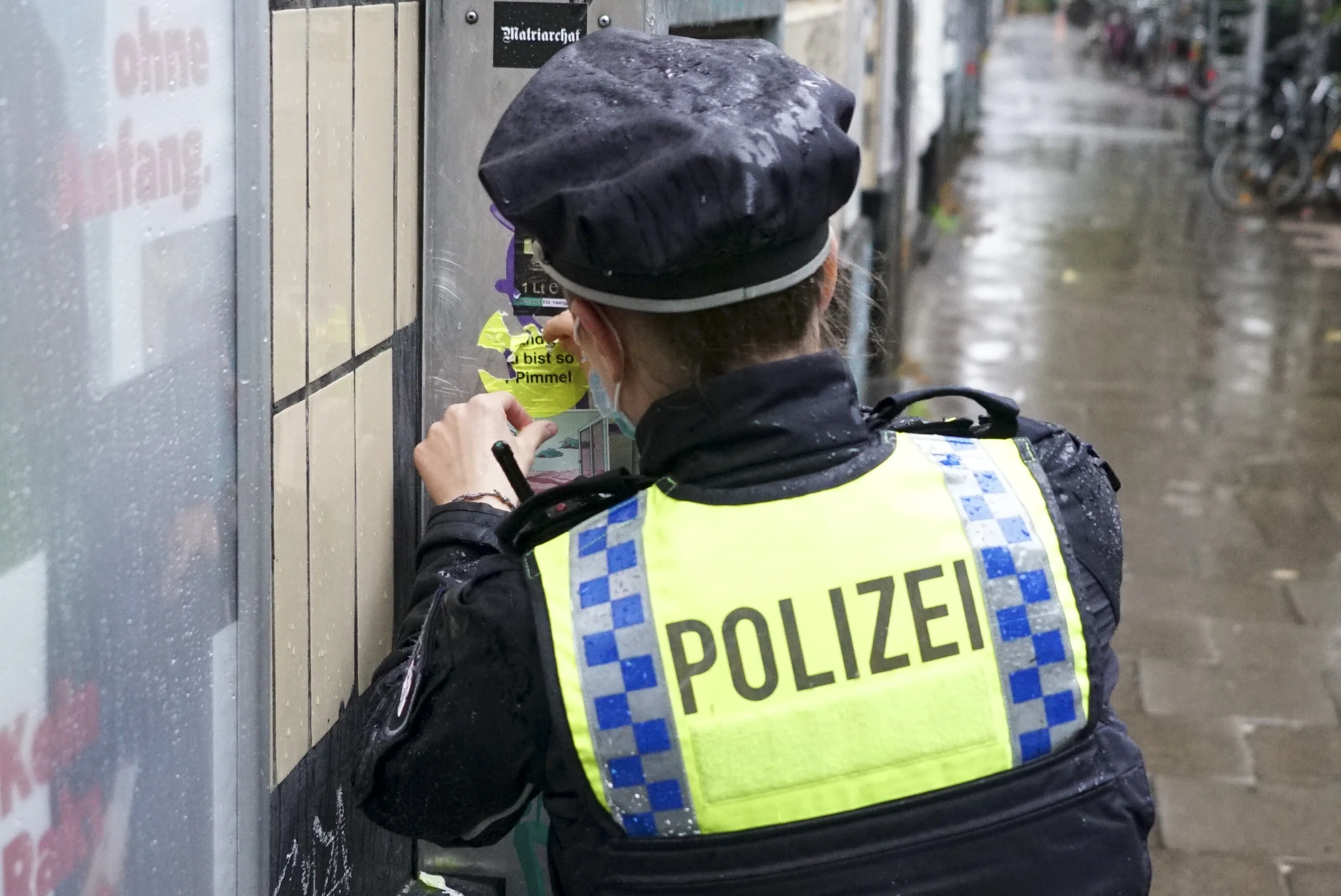 Polizistin entfernt einen Aufkleber von einer Wand