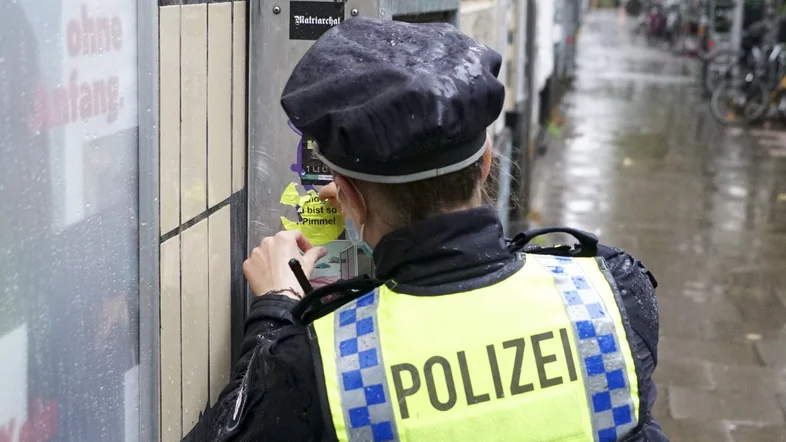 Polizistin entfernt einen Aufkleber von einer Wand