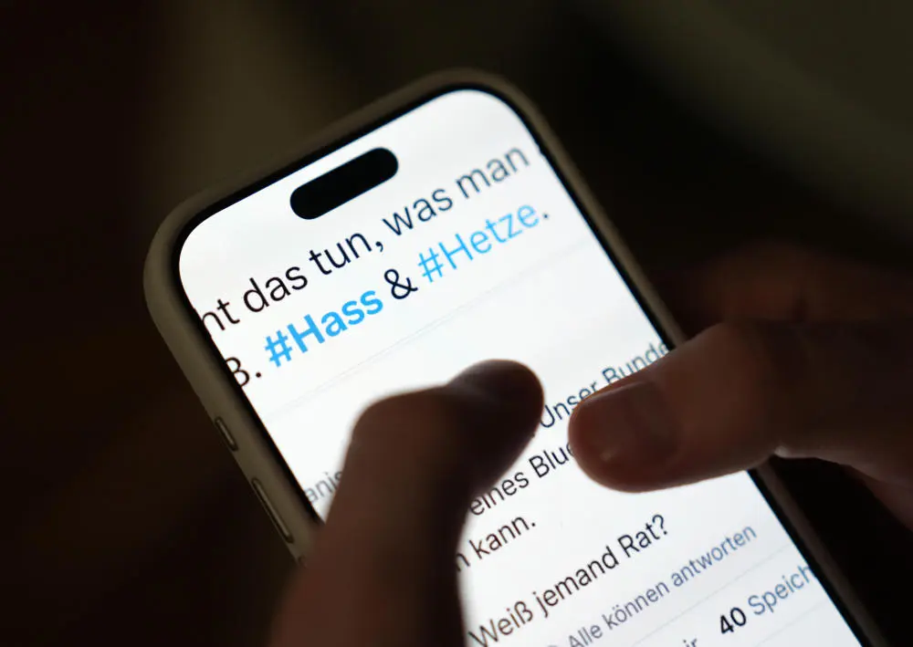 Der Bildschirm eines Smartphones mit den Wörtern Hass und Hetze