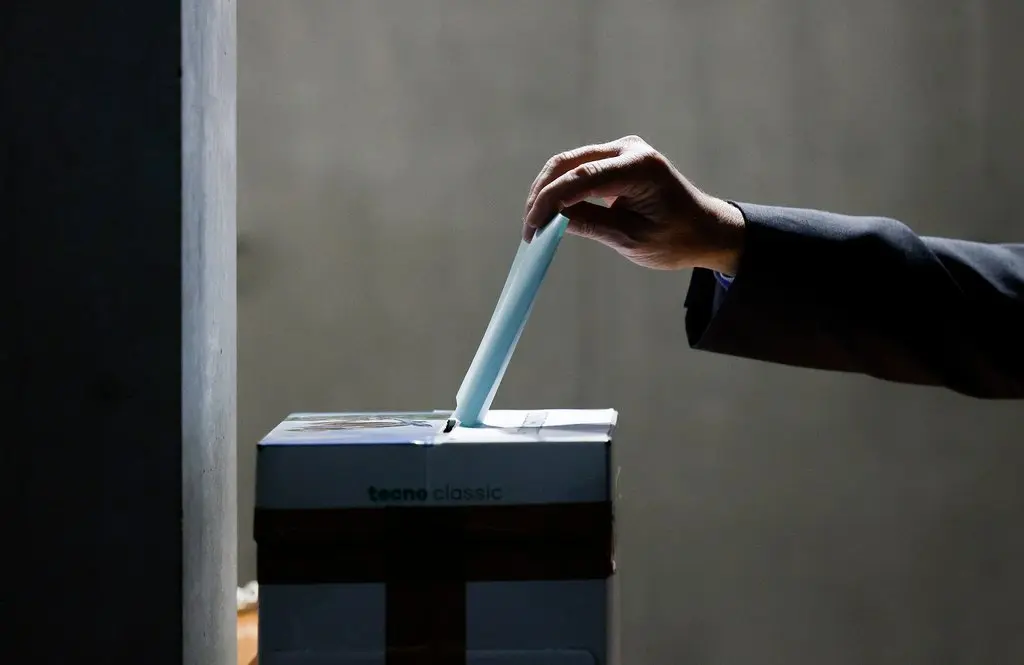 Stimmzettel wird in einen Wahlurnenkarton gesteckt