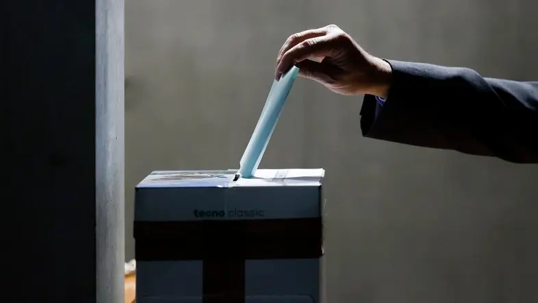 Stimmzettel wird in einen Wahlurnenkarton gesteckt