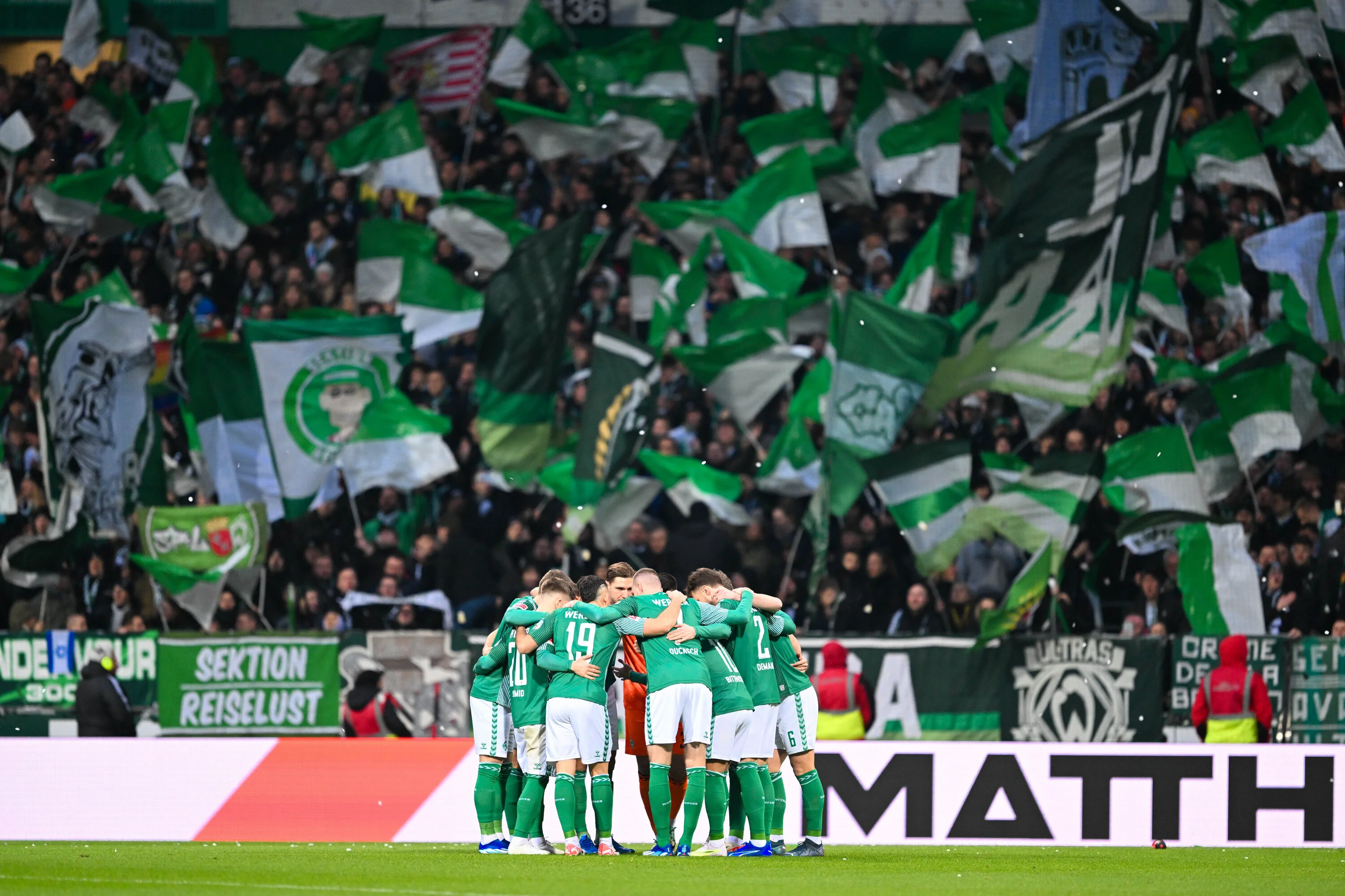 Spieler von Werder Bremen im Kreis vor der Kurve im Weserstadion